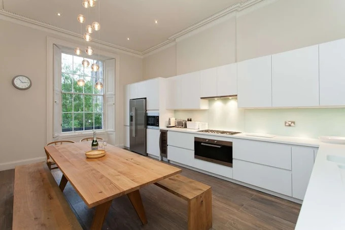 Modern white handleless kitchen with pendant lighting by SES Renovations